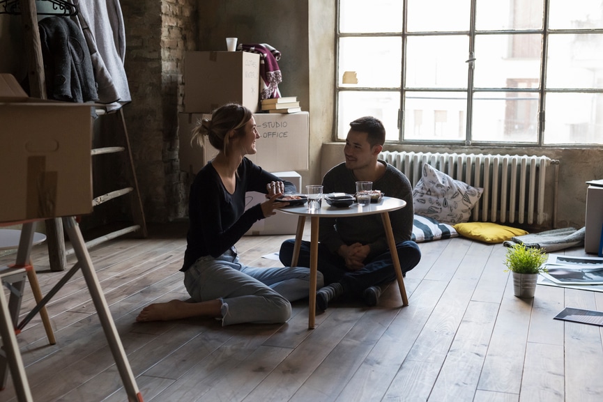 Young couple eating sushi in new home.